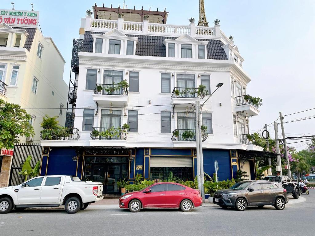 a white building with cars parked in front of it at Paris Hotel & Cafe in Vĩnh Long
