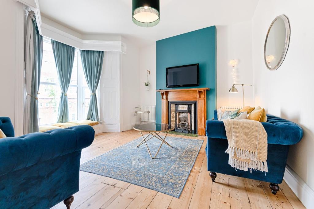 a living room with a blue couch and a fireplace at Ty Calon - 3 storey 1920s home, close to beach & the city- close to theatre- perfect for family & friend breaks or longer term for contractors, crew and cast in Swansea