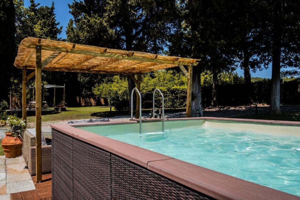 een zwembad met een houten pergola bij CASENUOVE III - Casale con giardino e piscina in Castiglioncello