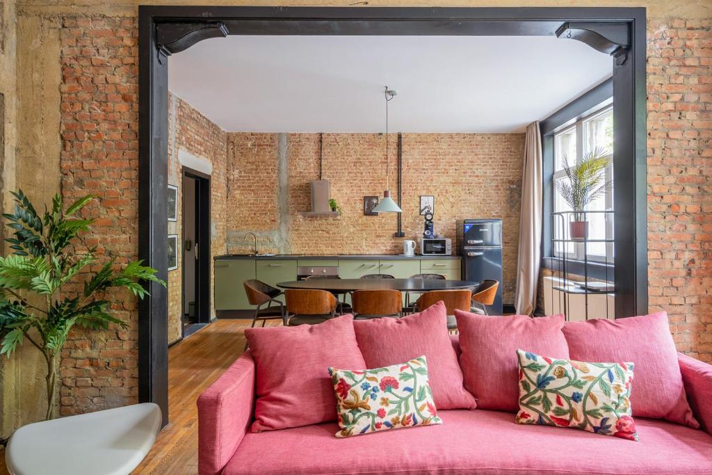 un salon décloisonné et une cuisine avec un canapé rose dans l'établissement Smartflats - the Brooklyn Antwerp, à Anvers