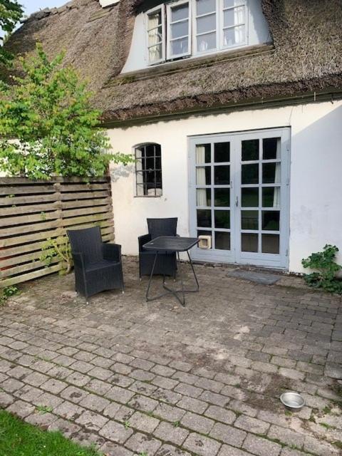 een patio met 2 stoelen en een tafel voor een huis bij Dyrlundgård in Helsinge