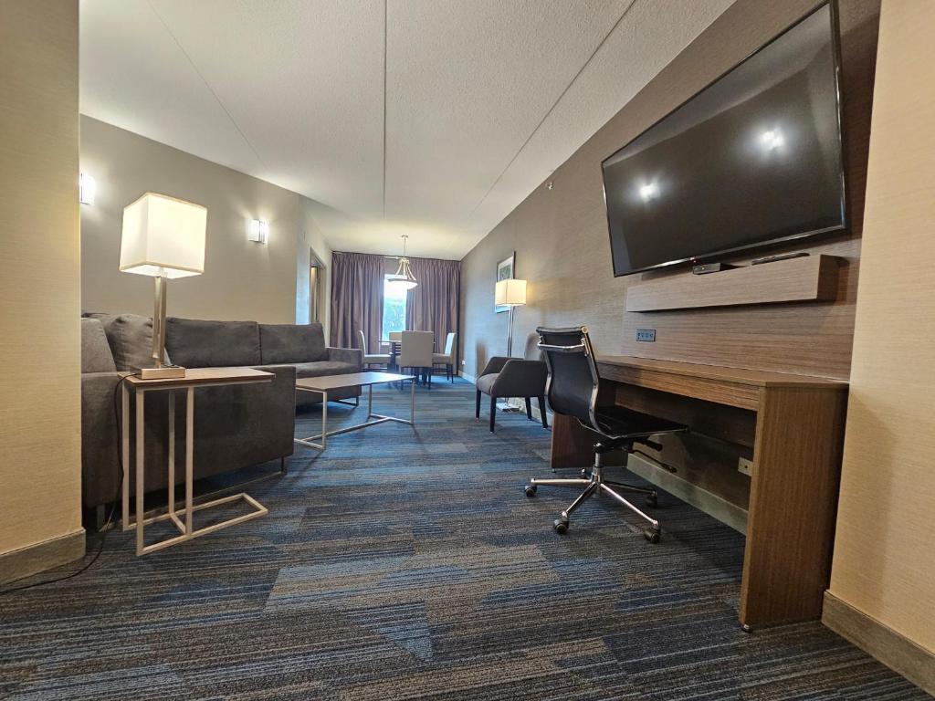 Clarion Hotel & Suites في براندون: غرفة في الفندق مع تلفزيون بشاشة مسطحة وغرفة معيشة