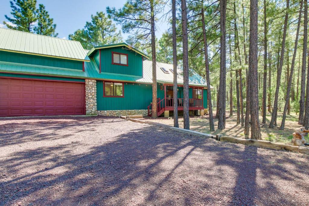 une maison verte avec un garage rouge dans les bois dans l'établissement Pinetop-Lakeside Family Home Near Rainbow Lake!, à Pinetop-Lakeside