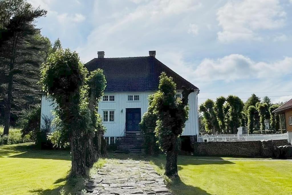 uma casa branca com duas árvores em frente em Bosvik Gård, nyrenovert leilighet i hovedhus fra 1756 em Risør