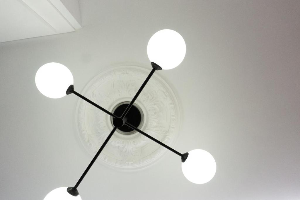 un reloj colgando del techo con tres luces en La Antigua Farmacia, en Hervás