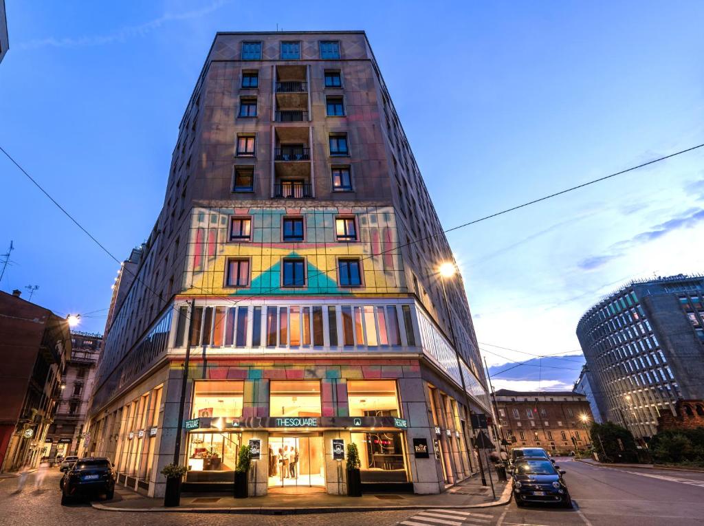 un edificio alto en una calle de la ciudad con coches aparcados delante en Hotel The Square Milano Duomo - Preferred Hotels & Resorts, en Milán