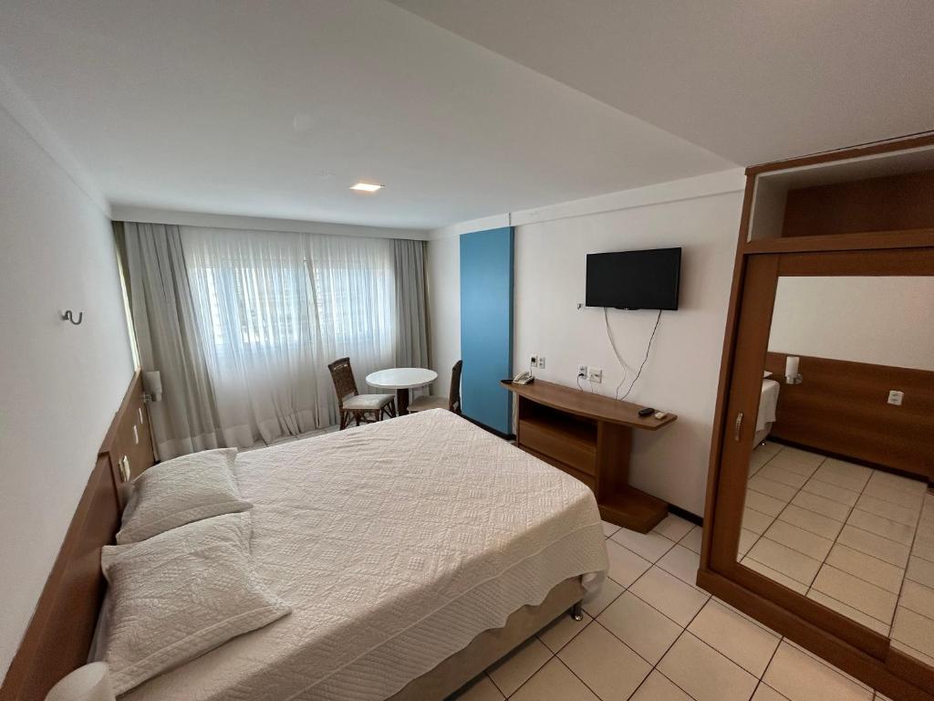 a bedroom with a bed and a desk and a television at PONTA NEeGRA FLAT - HOTEL MILOR in Natal