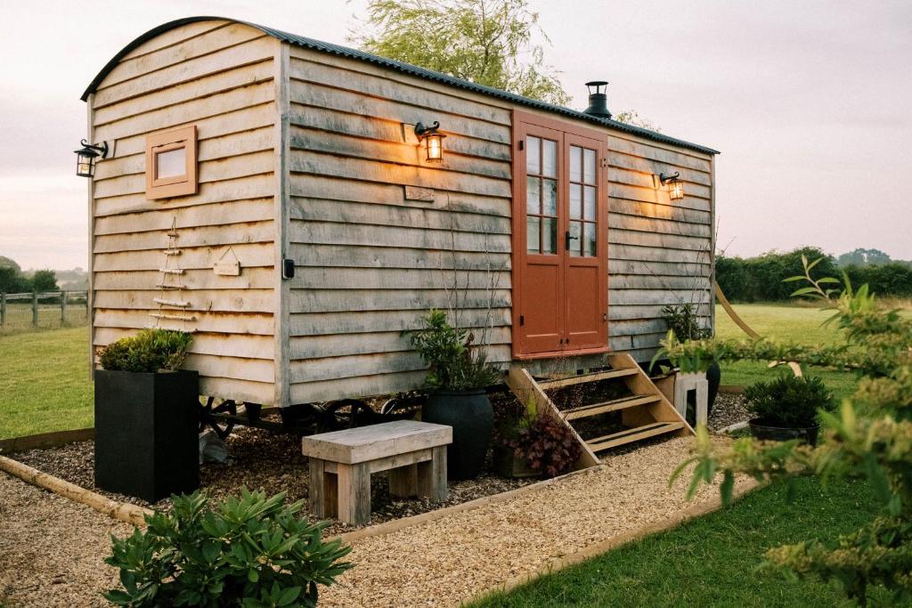 a tiny house in a garden with a red door at Bonnie's Shepherds Hut in Nottingham