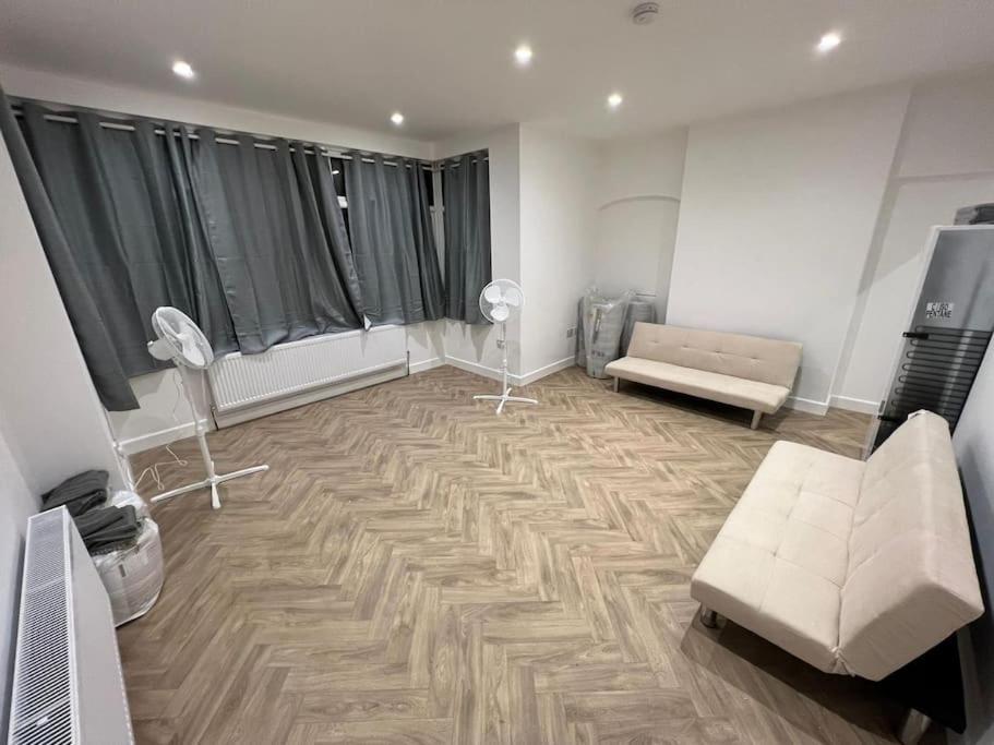 ein Wohnzimmer mit einem Sofa und 2 Stühlen sowie ein Zimmer mit einem Sofa in der Unterkunft Ground Flr 3-bed flat near Norbury Station in Norbury