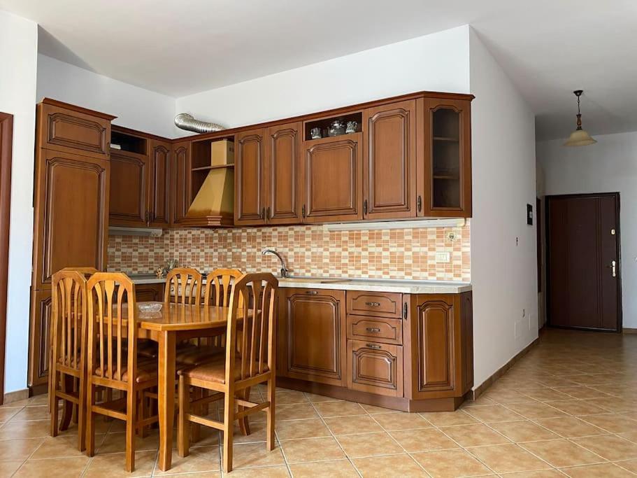a kitchen with wooden cabinets and a table and chairs at Roel apartments Shkodra Center in Shkodër