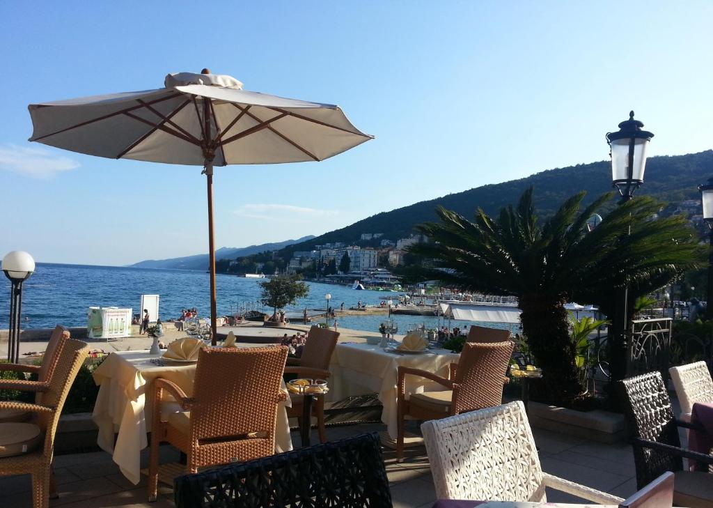 un tavolo con ombrellone, sedie e l'oceano di Apartment Kamelija a Opatija
