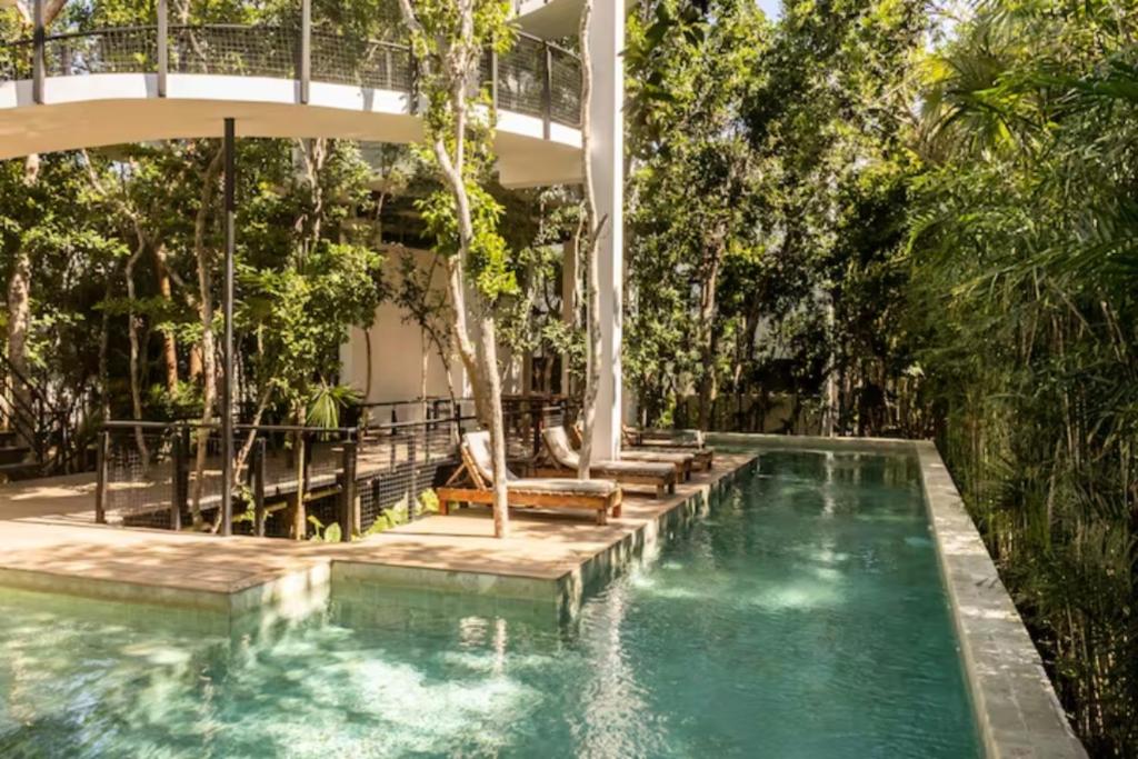 ein Schwimmbad mit einer Brücke darüber mit Bäumen in der Unterkunft Stunning Jungle House in Tulum TH15 Gym BBQ Private pool in Tulum