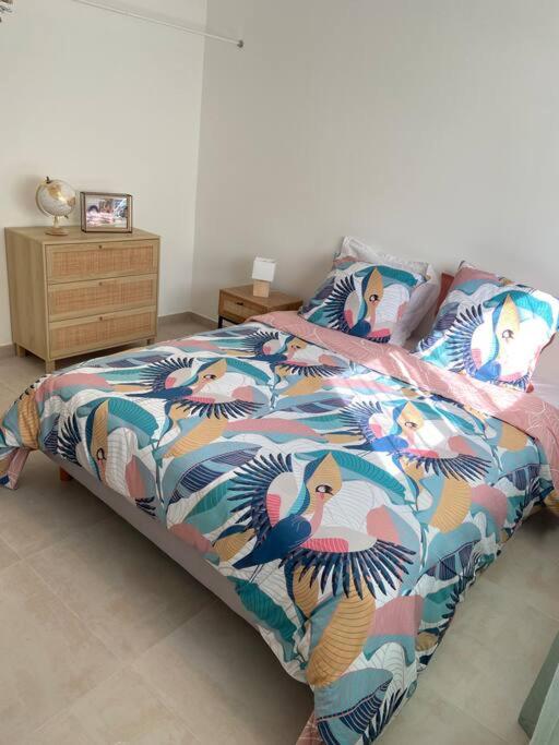 a bed with a colorful comforter with birds on it at Exceptionnelle Vue Mer Calvi - Piscine - T2 in Calvi