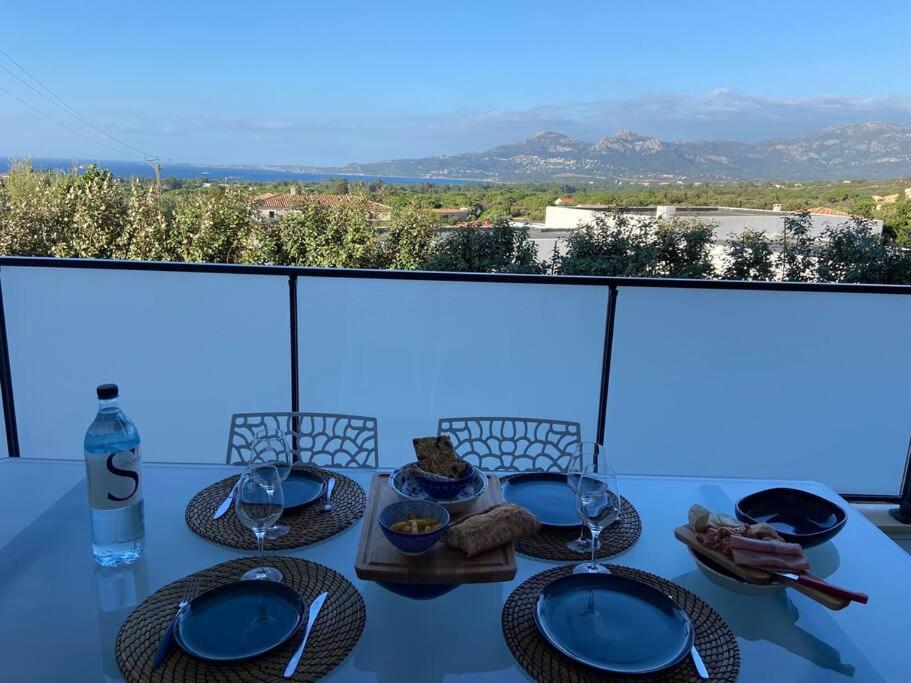 a table with plates of food on top of a balcony at Exceptionnelle Vue Mer Calvi - Piscine - T2 in Calvi