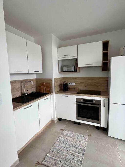 a kitchen with white cabinets and a sink and a refrigerator at Exceptionnelle Vue Mer Calvi - Piscine - T2 in Calvi