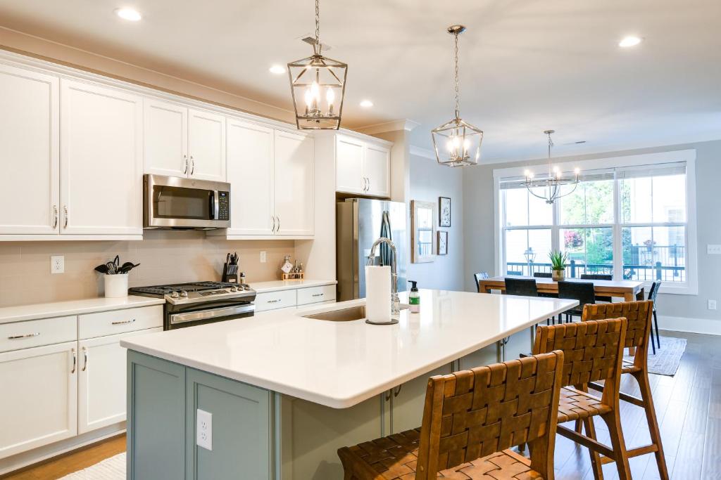 a kitchen with white cabinets and a kitchen island with chairs at Cozy South Carolina Abode - Steps from Main Street in Greenville