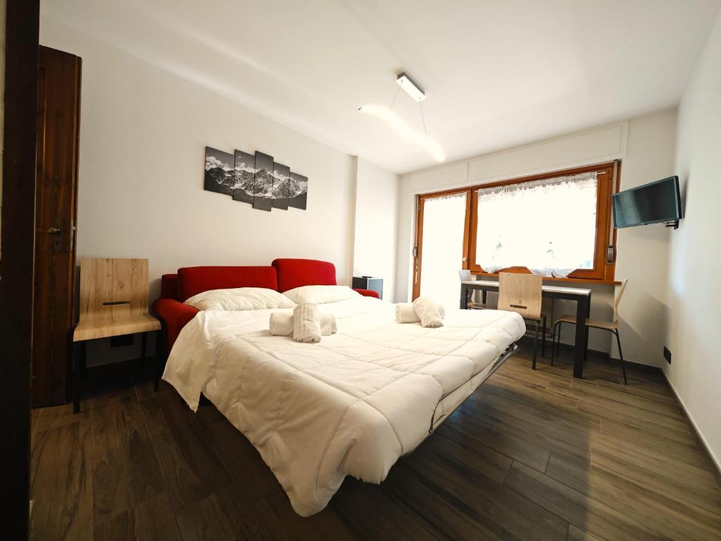 ein Schlafzimmer mit einem großen Bett und einem roten Sofa in der Unterkunft Hostdomus - City Center Apartment in Sestriere