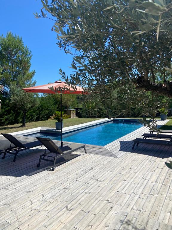 a pool with two chairs and a table and an umbrella at Maison proche du pic Saint Loup in Saint-Jean-de-Cuculles