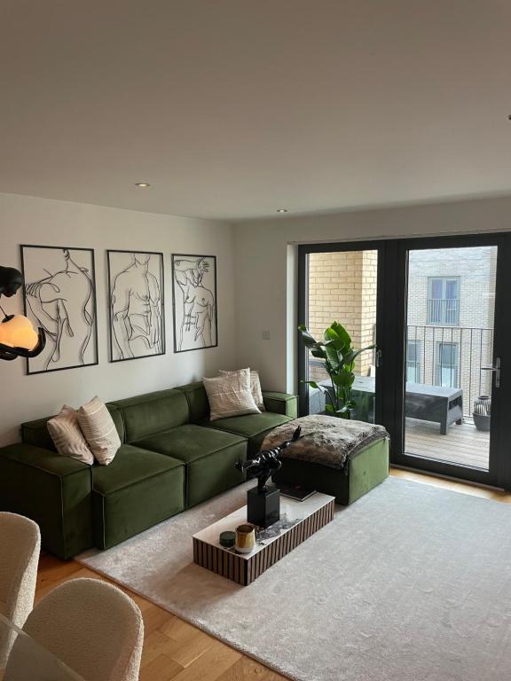 a living room with a green couch and a large window at Cosy bedroom in Luxury apartment in London