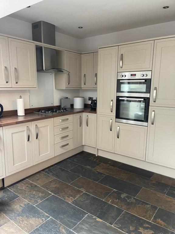 a kitchen with white cabinets and a tile floor at Heart of Cockermouth Gem 4 bedrooms 6 beds 2 bathrooms in Cockermouth