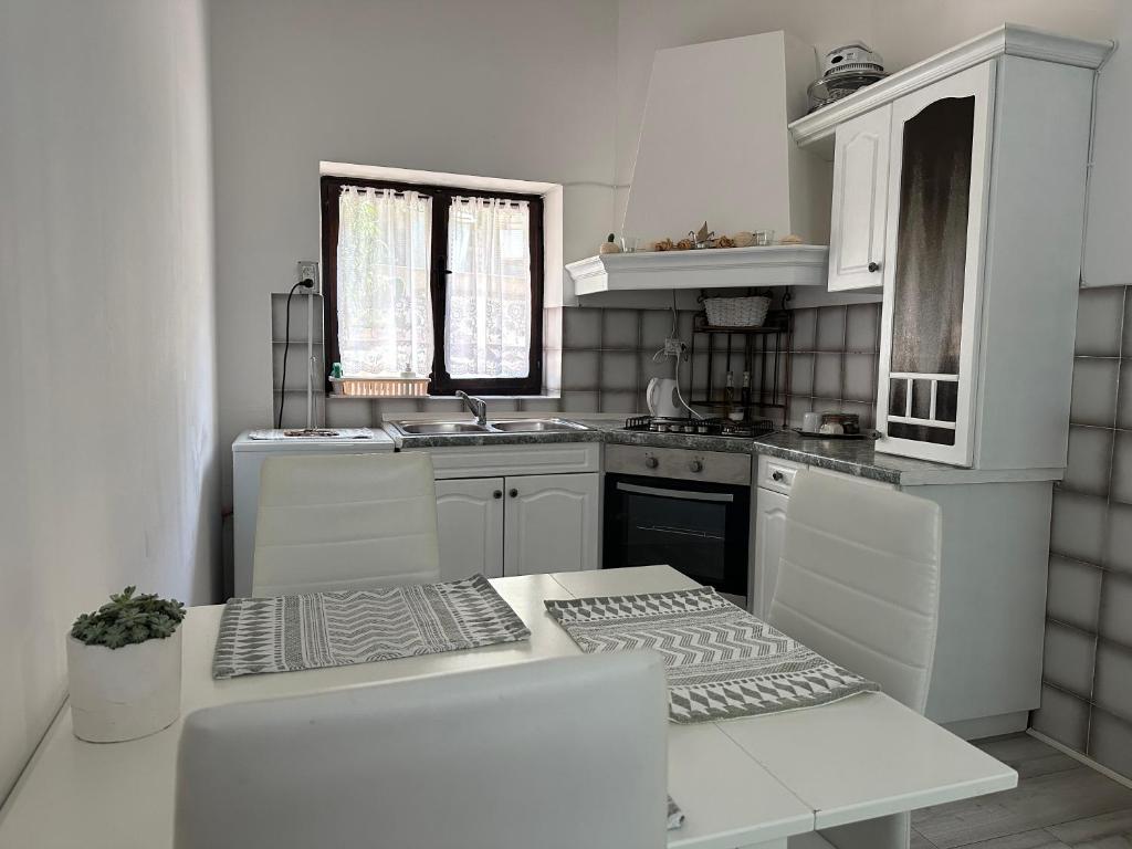 una cucina bianca con mobili bianchi e un lavello di Quiet countryside apartments near the city and the sea a Capodistria