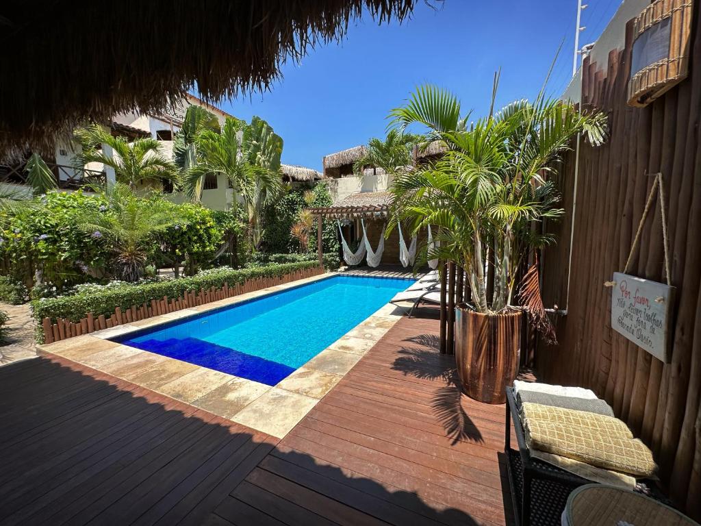 a swimming pool in a yard with a wooden deck at Pousada Oasis Paracuru in Paracuru