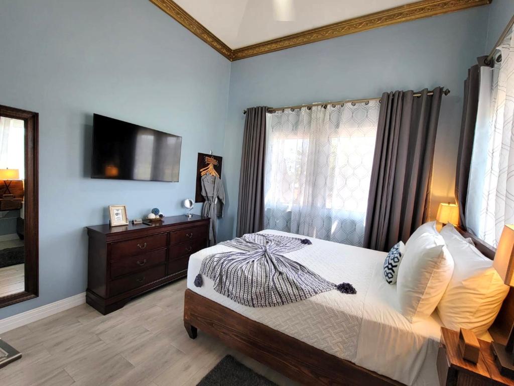 a bedroom with a bed and a dresser and a television at Villa Panorama in Montego Bay