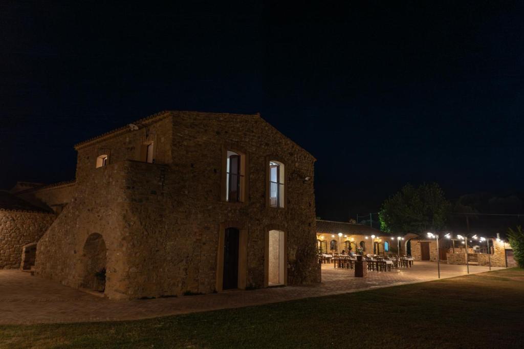 um edifício de pedra com mesas e luzes à noite em Agriturismo Fattoria San Sebastiano em Strongoli