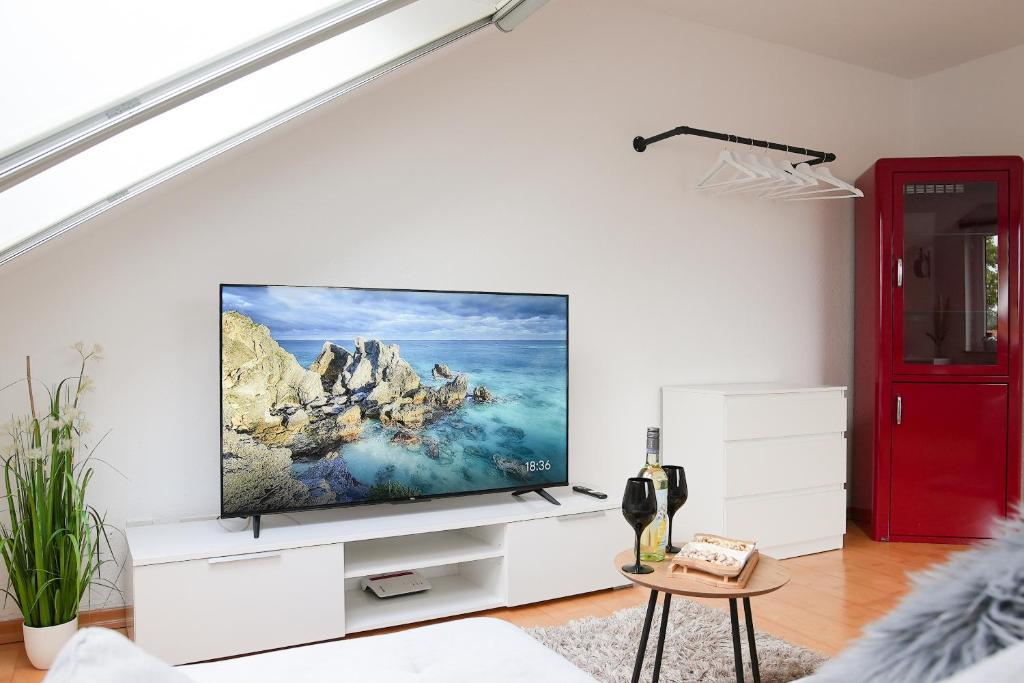 uma sala de estar com uma televisão de ecrã plano numa parede branca em Remark Studios - Wohnung für 6 in Großburgwedel em Burgwedel