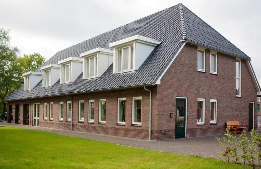 een groot gebouw van rode baksteen met witte ramen bij De Valkhoeve in Mill