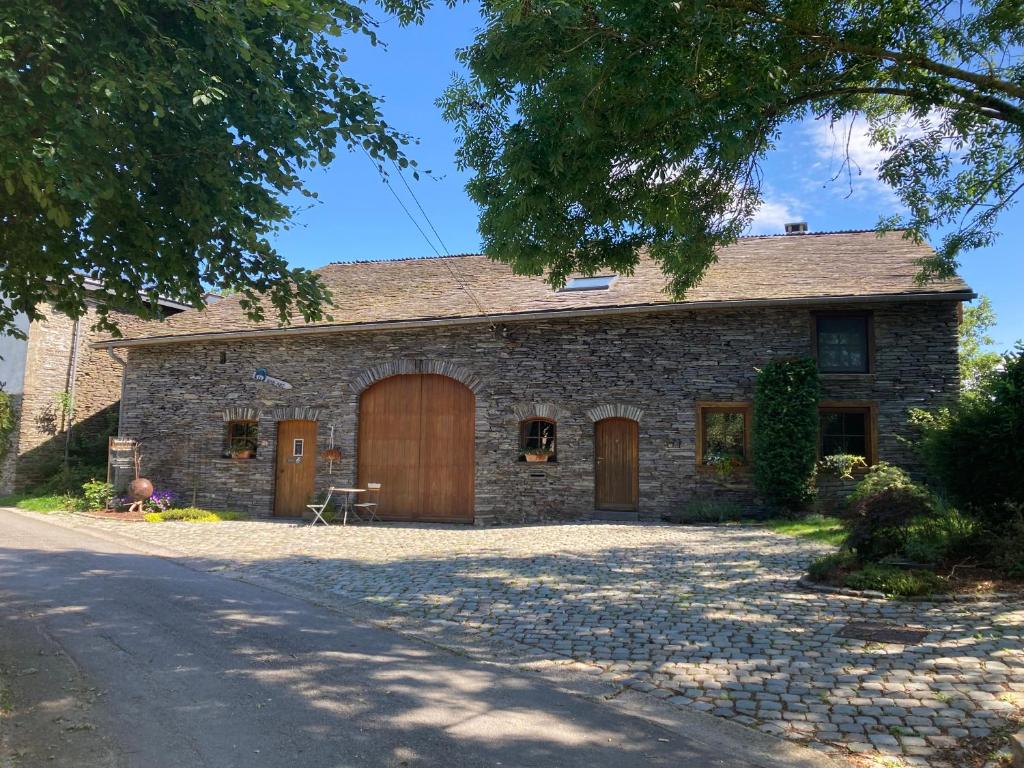 a stone house with a garage and a driveway at Le Temps d'une Fugue in Lierneux