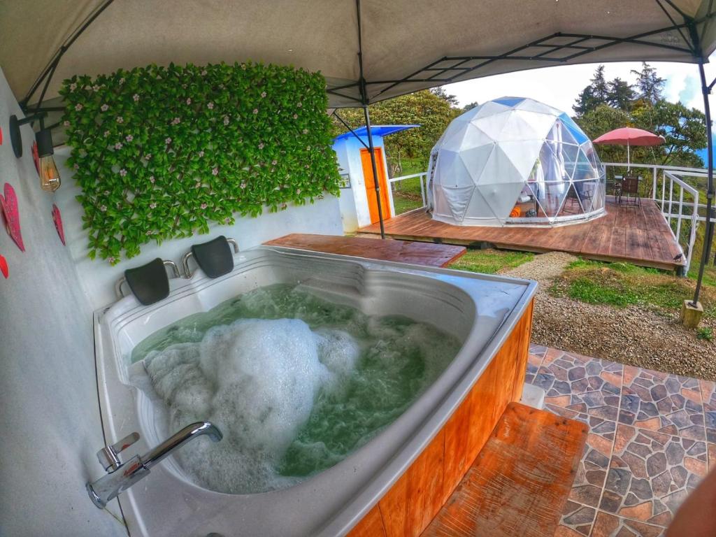 a bath tub with water in it with a tent in the background at Glamping Campestre Uriyahu in Macanal