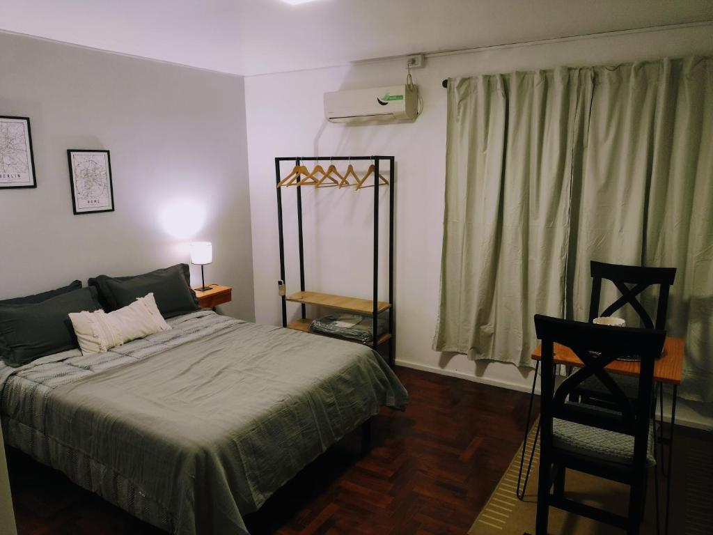 ein Schlafzimmer mit einem Bett, einem Stuhl und einem Fenster in der Unterkunft Monoambiente 76 in Mendoza