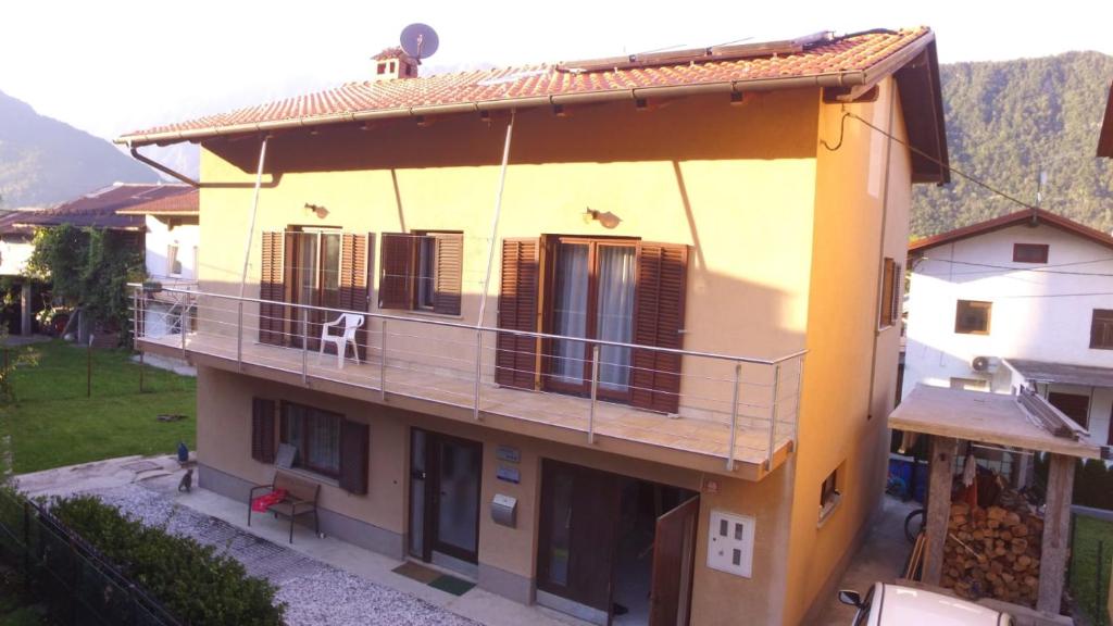 una casa amarilla con un perro sentado en un balcón en Apartment Green Valley, en Idrsko