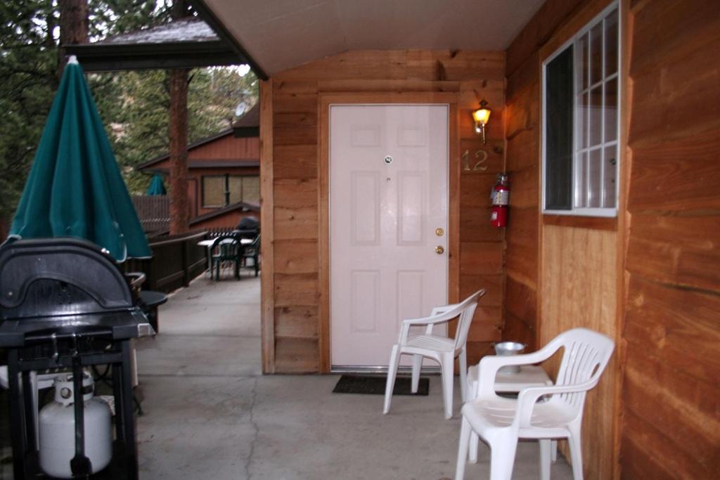 a porch with white chairs and a white door at Timber Creek Chalets- 12 chalet in Estes Park