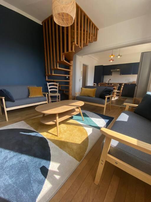 a living room with couches and tables and a staircase at joli duplex centre ville 5 min à pied de la gare sncf in La Loupe