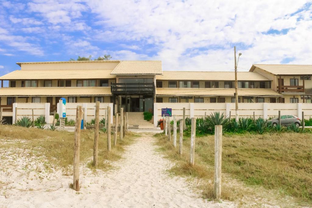 a building on the beach with a pathway in front of it at Pousada do Albatroz in Cabo Frio