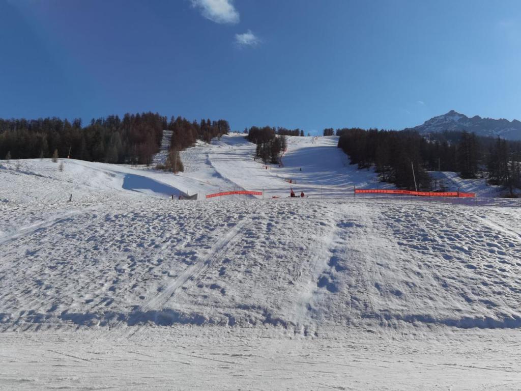 uma pista de esqui coberta de neve com pessoas a esquiar por ela em APPARTEMENT PIED DES PISTES SUPER SAUZE em Enchastrayes