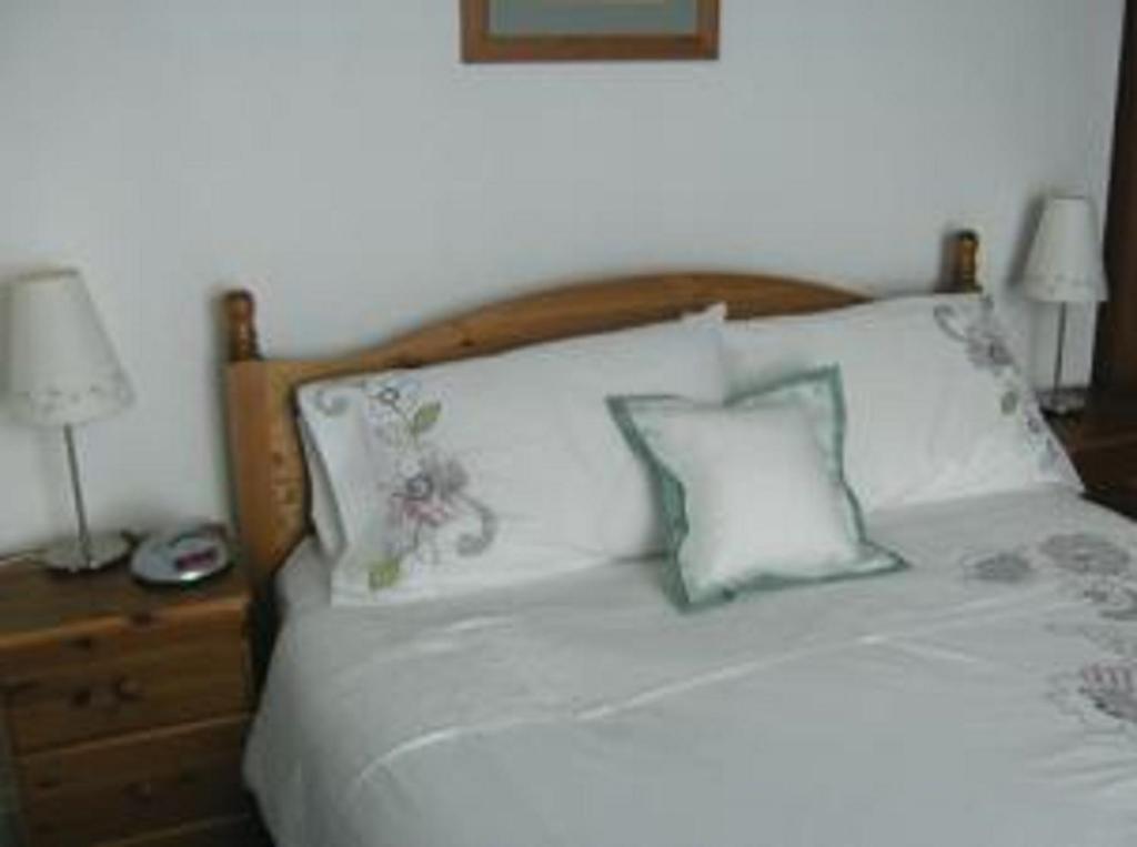 a white bed with two pillows and a wooden headboard at The Caraneal in Plymouth