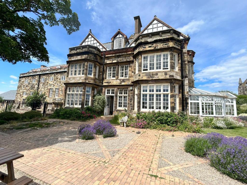 - un vieux bâtiment en pierre avec des fenêtres et des fleurs dans l'établissement YHA Whitby, à Whitby