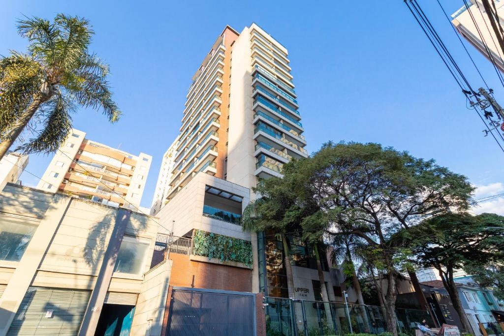 um edifício alto e branco com árvores em frente em Predio completo com piscina no Itaim Bibi proximo a Faria Lima - Upper Itaim em São Paulo