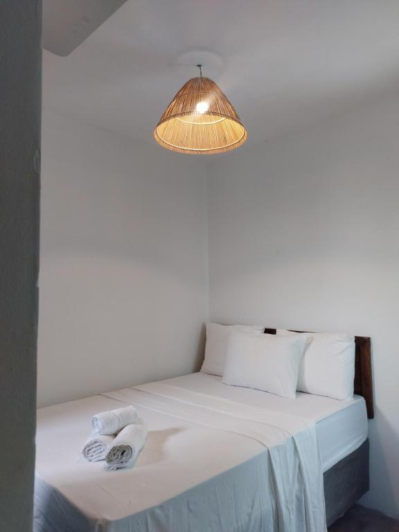 a bed in a room with a lamp and towels at Pousada Rocas Beach in Pôrto de Pedras