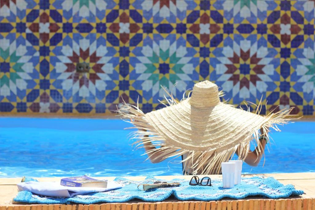 um chapéu de palha e óculos de sol sentados numa mesa ao lado de uma piscina em Palais didi em Meknès