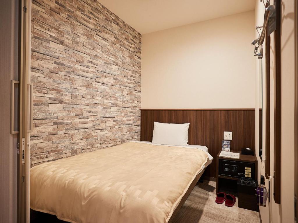 那霸的住宿－Grand Cabin Hotel Naha Oroku - Vacation STAY 46864v，一间卧室设有一张床和砖墙