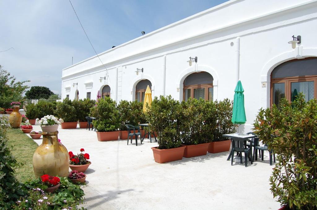 un edificio blanco con mesas, sillas y macetas en La Piccola Masseria en Cisternino