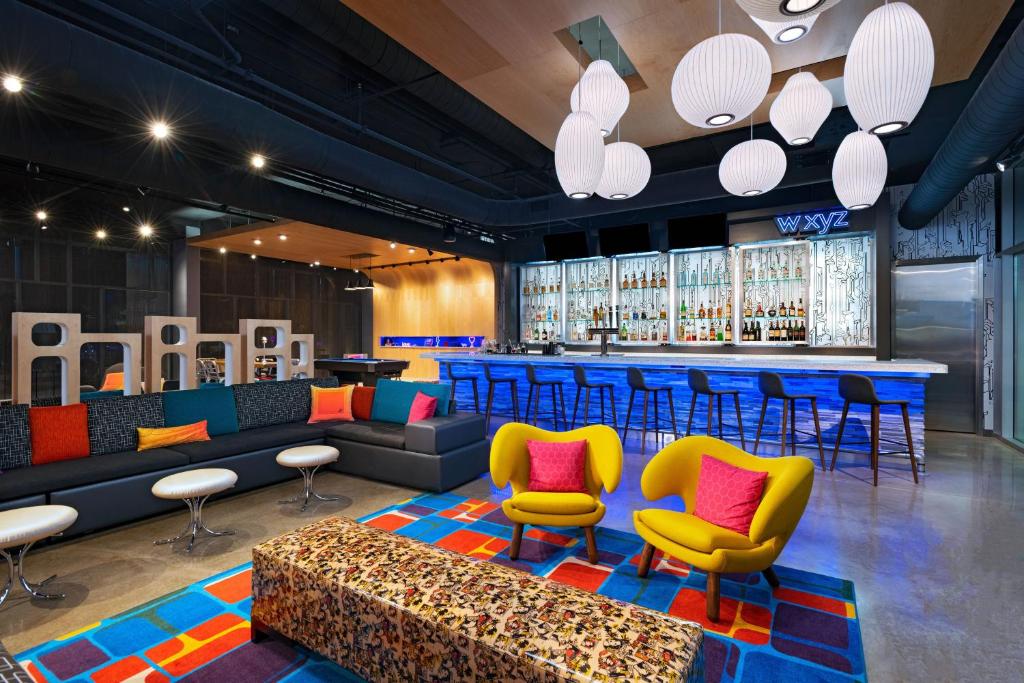 a lobby with a bar with colorful chairs and a couch at Aloft Waco Downtown in Waco