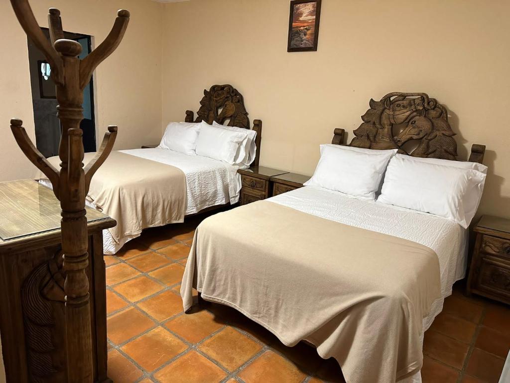 um quarto de hotel com duas camas com lençóis brancos em Bebelines inn dos em San Miguel de Allende