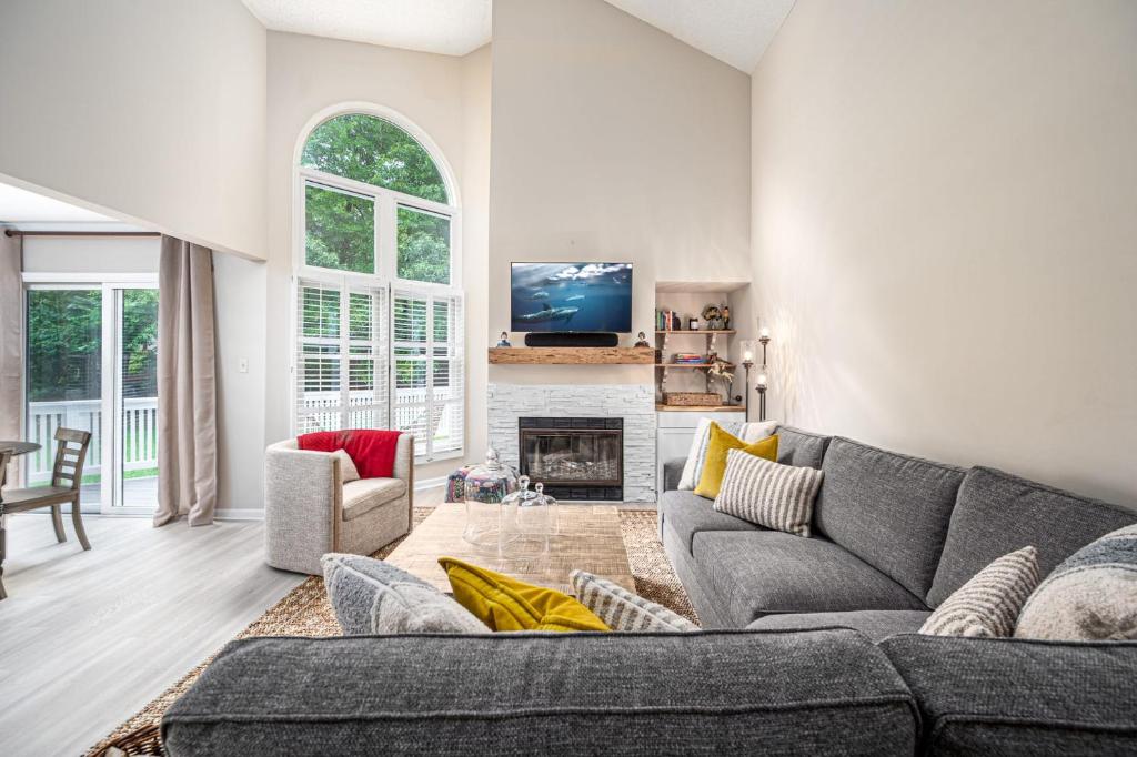 uma sala de estar com um sofá cinzento e uma lareira em The Cozy Cottage - 10 Min From UNC em Chapel Hill