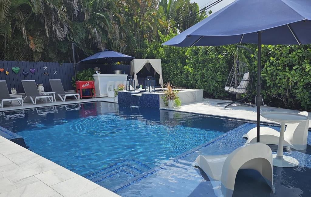 a swimming pool with an umbrella and chairs and a table at Casa806 Men Only Guest House in Fort Lauderdale