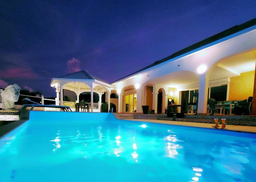 a swimming pool in front of a house at night at RESIDENCE VILLA SEA PEARL in Saint Martin